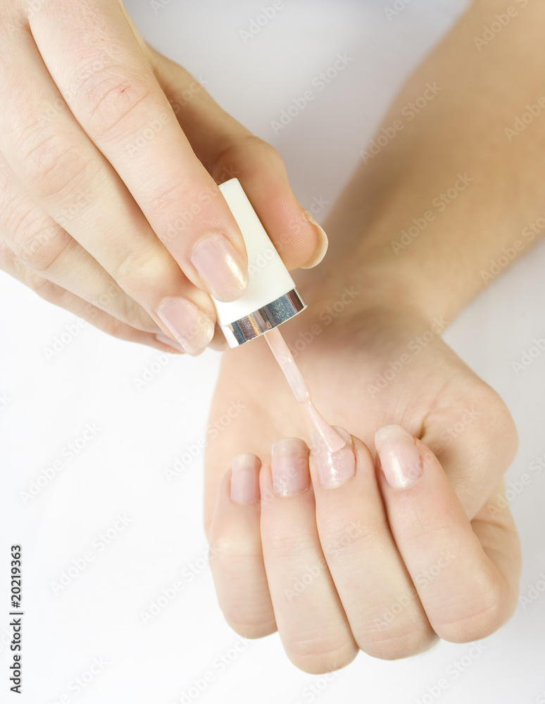young woman applying pink nail polish on her fingers young woman applying pink nail polish on her fingers