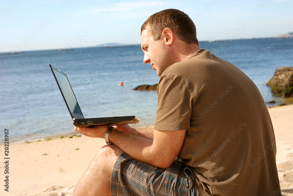man with computer at beach