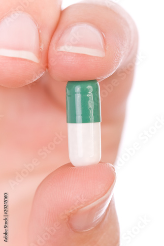Hand holding a capsule or pill close up
