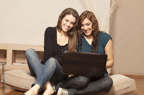 Happy young women with laptop on the floor