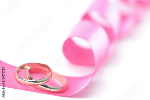 Gold wedding rings over pink ribbon isolated
