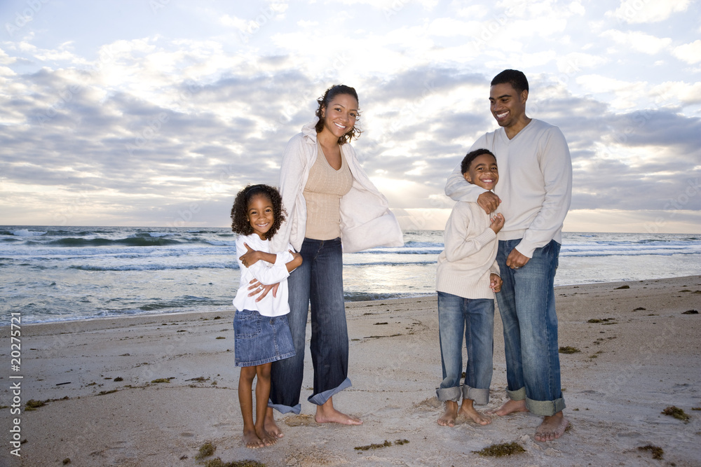 Happy African-American family with two children hugging on beach Happy African-American family with two children hugging on beach