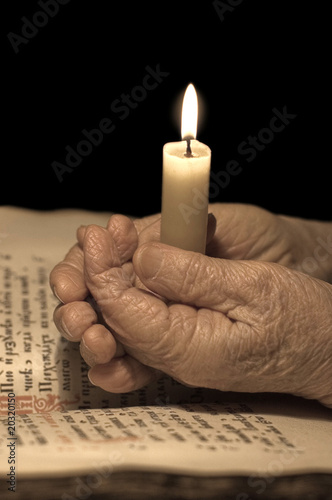 Old female hands with a candle