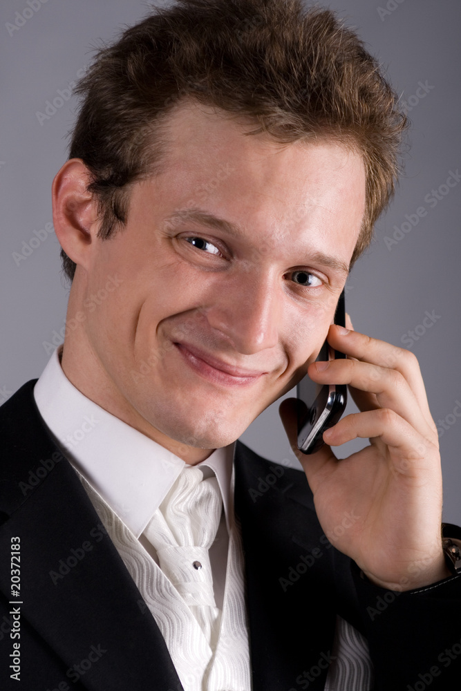 attractive young man in a dress coat talks by a mobile phone attractive young man in a dress coat talks by a mobile phone