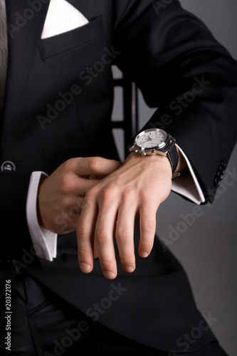 hands of the man in a black suit and expensive watch