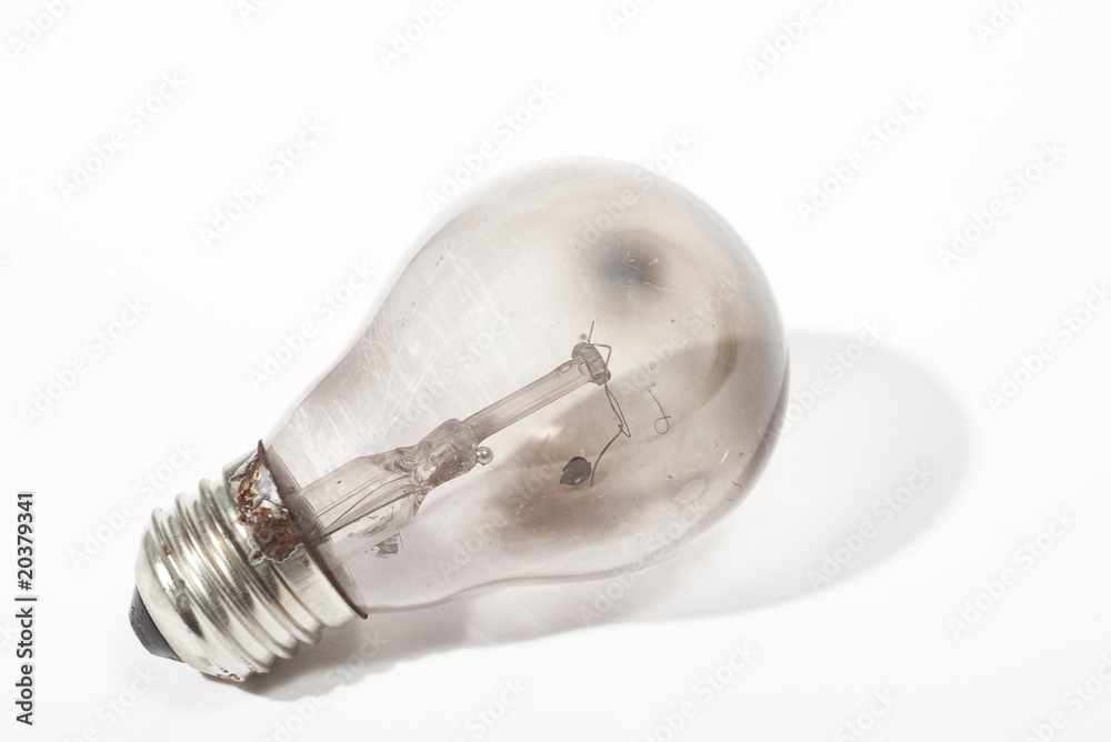 Burnt out light bulb against white background with shadow Burnt out light bulb against white background with shadow