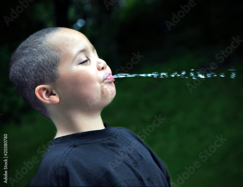 Latino boy spitting water photo