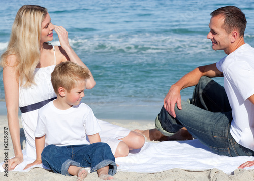Smiling parents with their son sitting on the sand