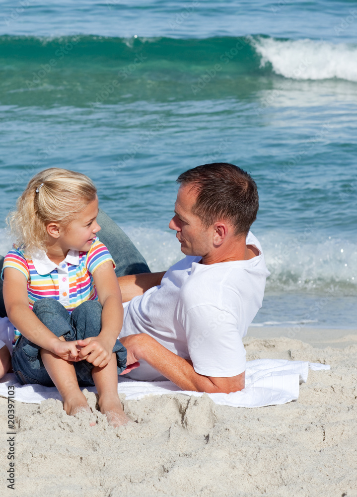 Adorable little girl and her father sitting on the sand Adorable little girl and her father sitting on the sand
