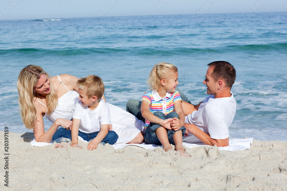 Happy family sitting on the sand