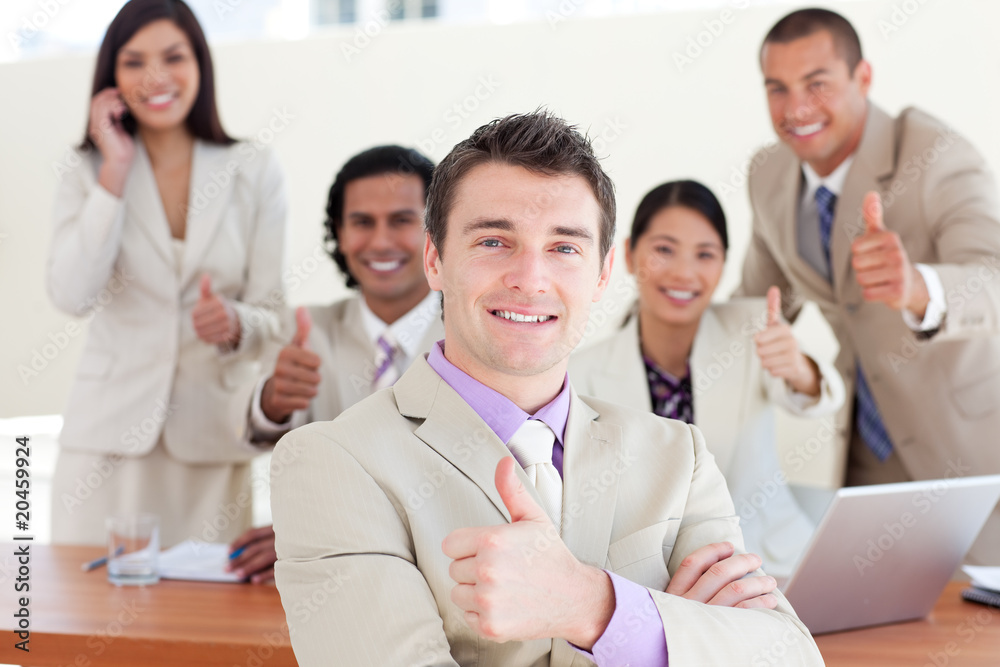 Successful manager in front of his team with thumbs up Successful manager in front of his team with thumbs up