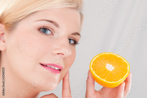Young beautiful woman with healthy skin and orange fruit