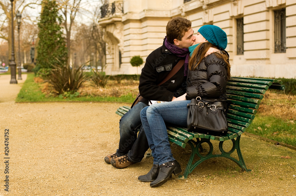 Young couple in love kissing on a bench