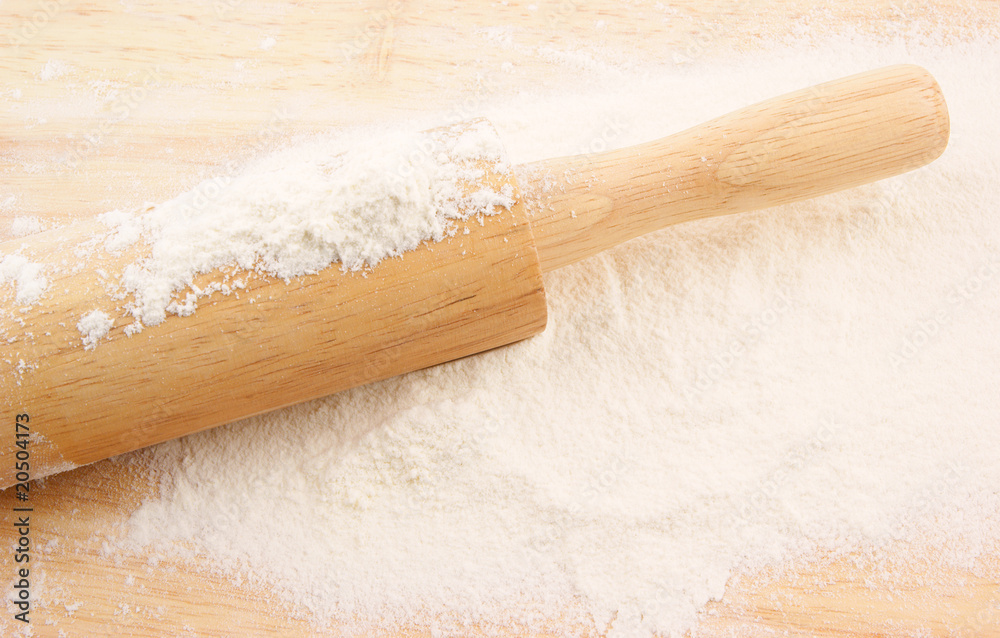 Flour and rolling pin on wooden background