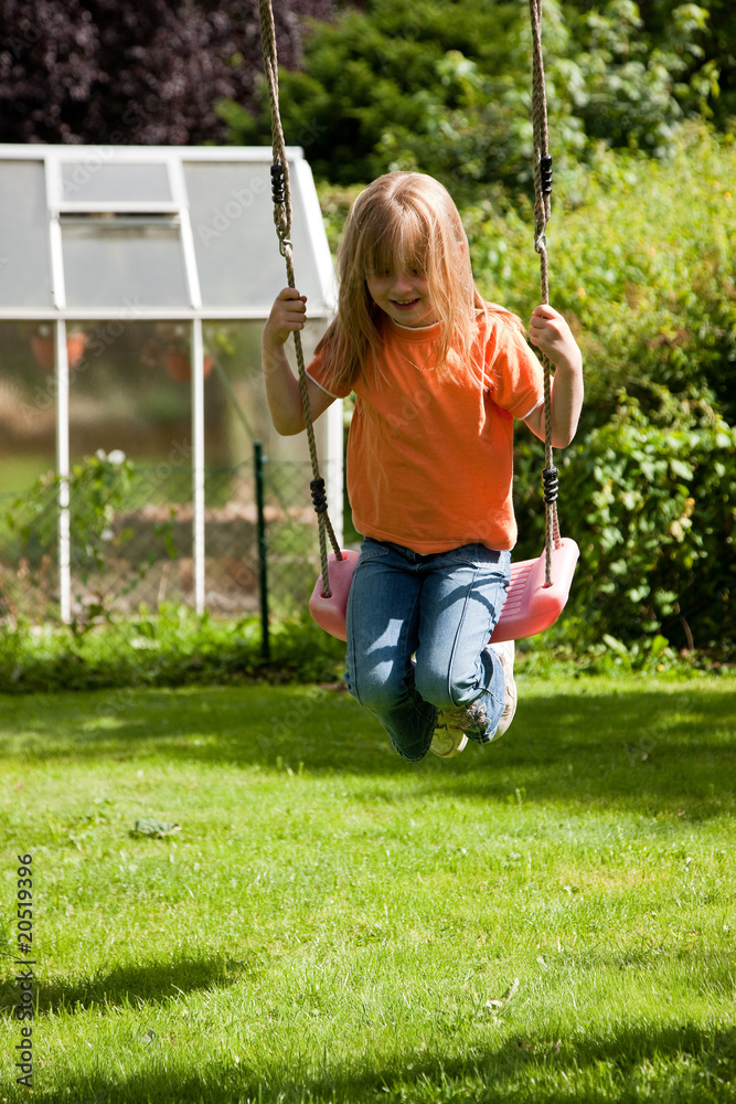 Girl child on swing in the garden