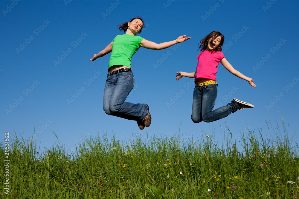 Mother and daughter jumping, running against blue sky Mother and daughter jumping, running against blue sky