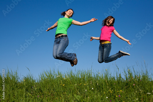 Mother and daughter jumping  running against blue sky