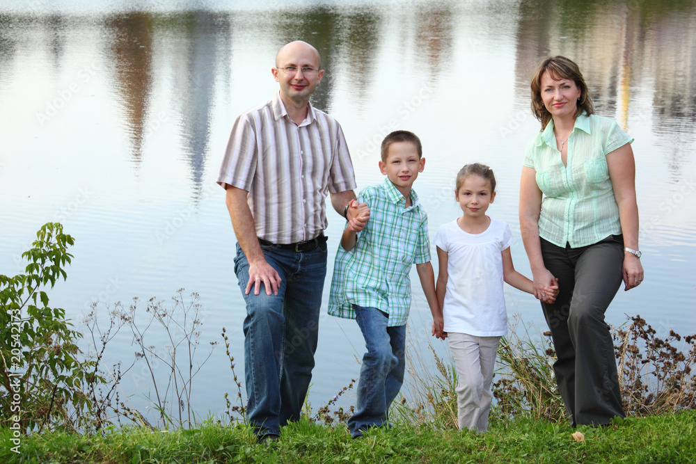 family  are standing near pond