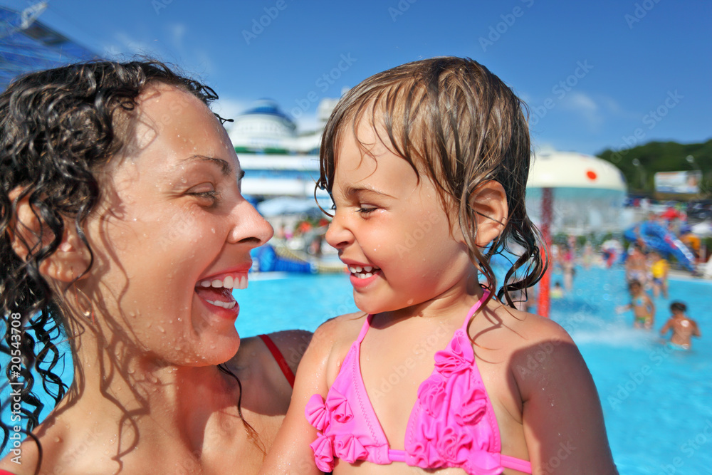 Smiling beautiful woman and little girl bathing in pool Smiling beautiful woman and little girl bathing in pool