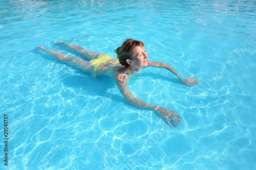 young beautiful woman swimming in yellow bikini in paddling pool