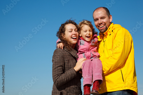 Happy parents together with daughter on hands bright sunny day