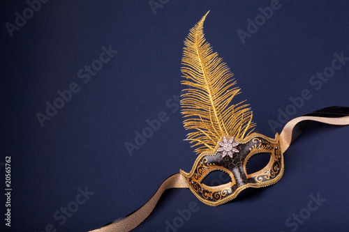 black and gold feathered mask on a dark background