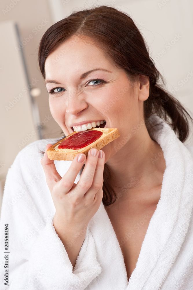 Young woman eating toast for breakfast in kitchen