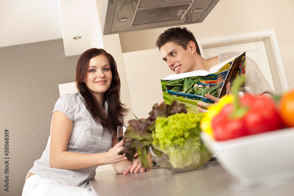 Young couple in kitchen choosing recipe from cookbook Young couple in kitchen choosing recipe from cookbook