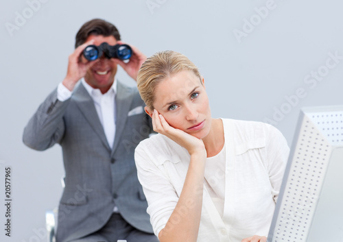 Картината върху платно Blond businesswoman annoyed by a man looking through binoculars