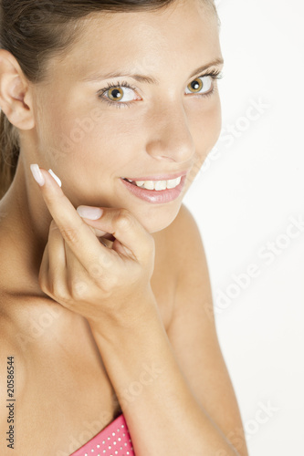 portrait of woman putting cream on face