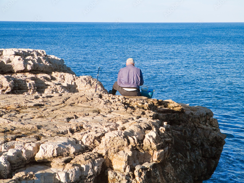 Fisherman sitting on the rocks.