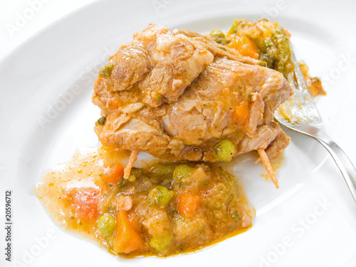 Meat roulade with vegetable soup on white dish.