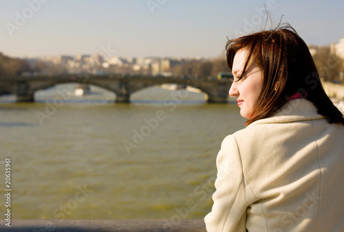 Beautiful woman in Paris on the Seine embankment, contemplating