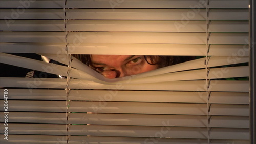 man shooting through the blinds