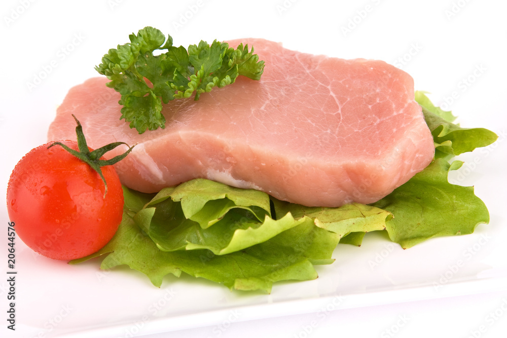 Stück rohes Fleisch mit Salat und Tomate isoliert