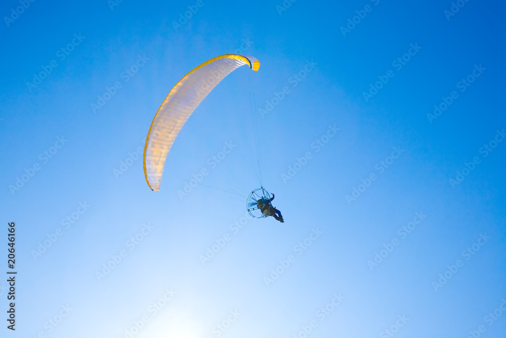 Yellow paraglider in serene cloudless blue sky Yellow paraglider in serene cloudless blue sky
