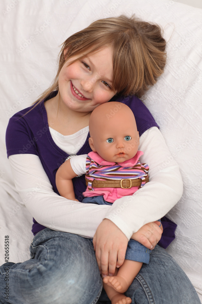 Little girl with doll on sofa Little girl with doll on sofa