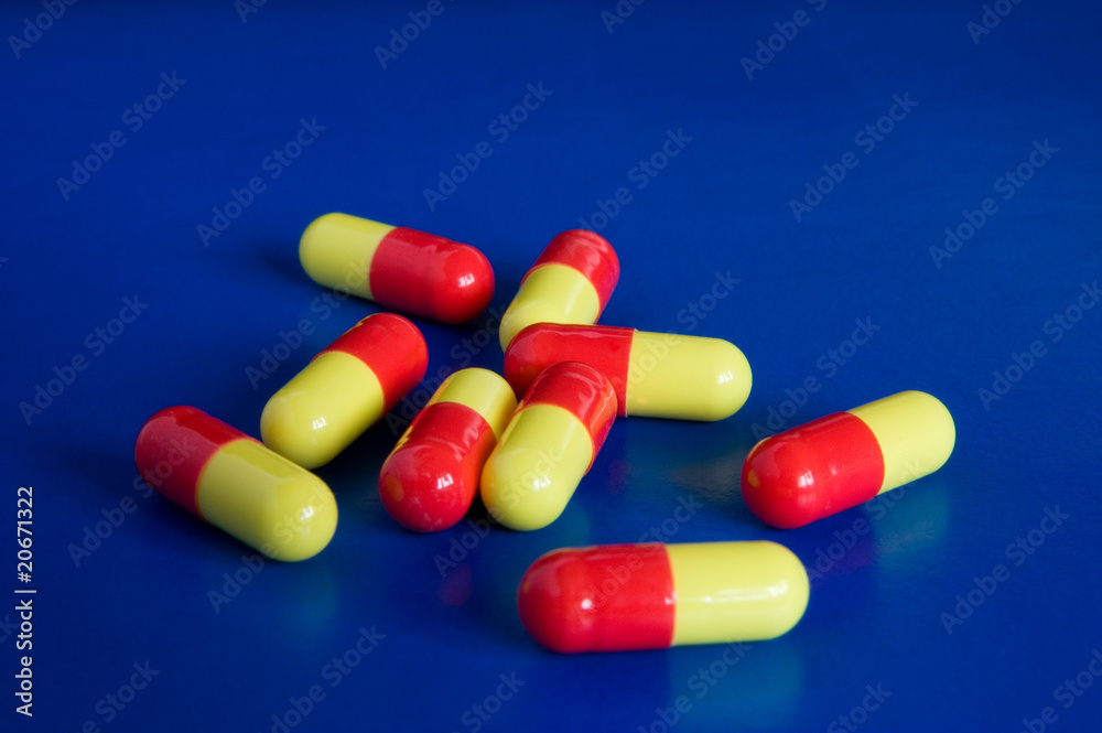 Several redandyellow oblong pills against blue background Stock Photo
