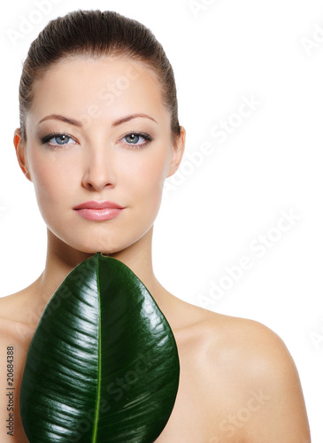 Beautiful fresh woman's face with large green leaf photo