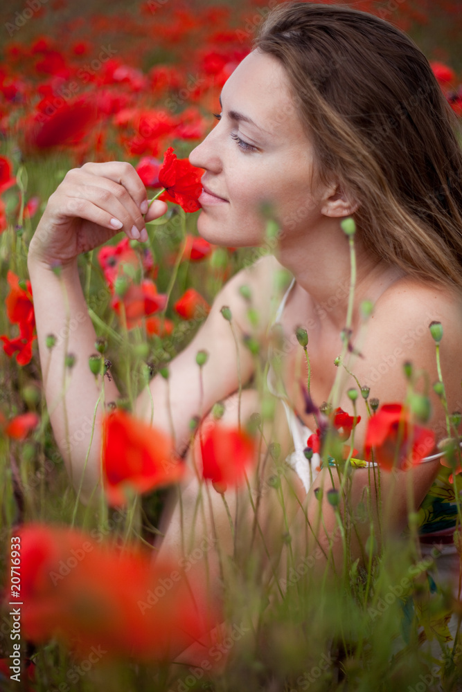 Naklejka premium girl sitting in a field of poppies