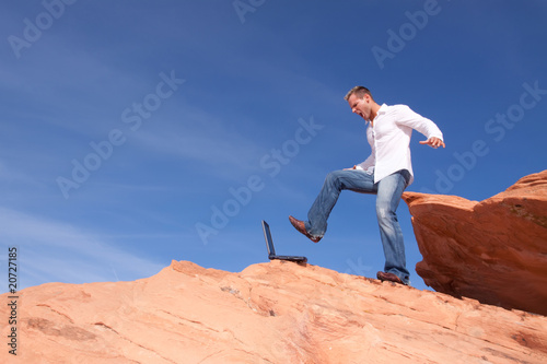 Angrry businessman kicking his laptop