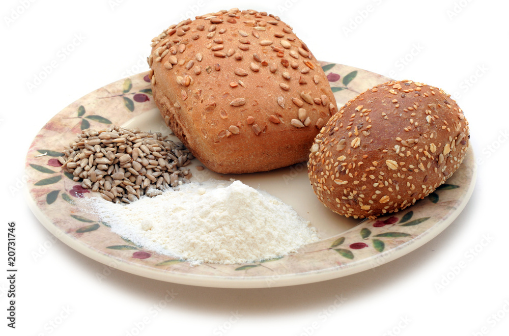 Whole-meal rolls, sunflower grain and flour on the plate Whole-meal rolls, sunflower grain and flour on the plate