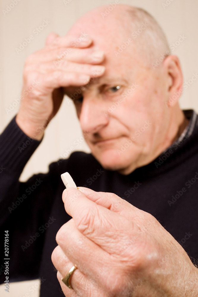 Fototapeta premium Senior older man with headache holding tablet or pill