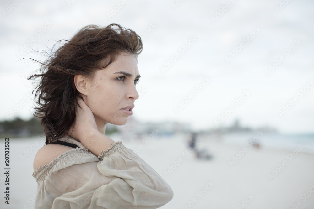 Woman on the beach touching her neck Woman on the beach touching her neck