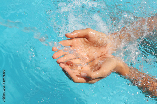 woman's palms catching splashing water over blue background