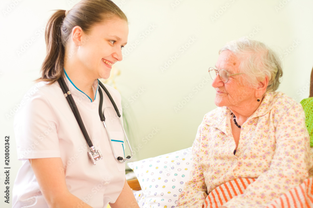 A young doctor and elderly sick woman socialising A young doctor and elderly sick woman socialising