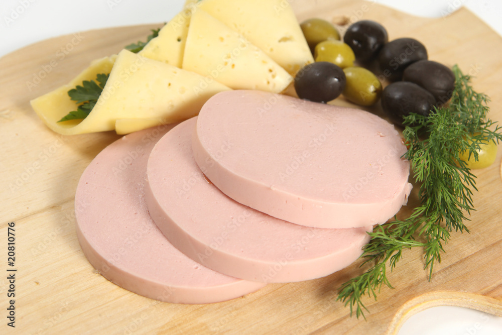 Sliced food arrangement with sausage, cheese, olives and greener