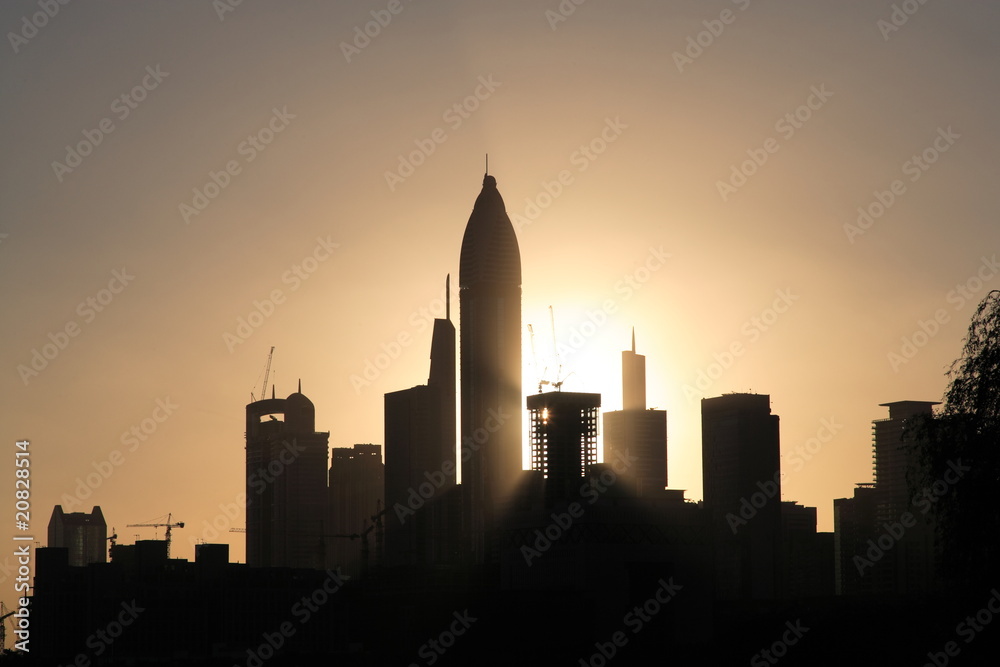 Sunset over Dubai with many towers in front.