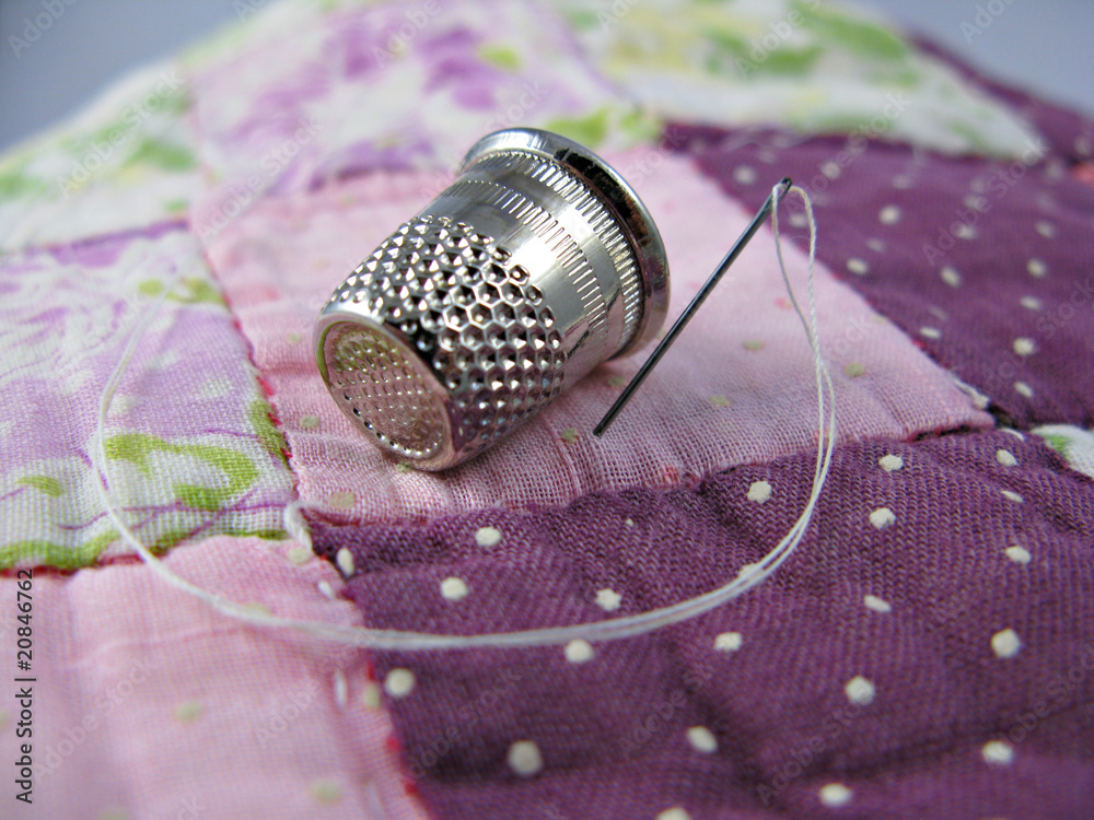 Silver colored thimble on an old antique patchwork quilt - obrazy, fototapety, plakaty 