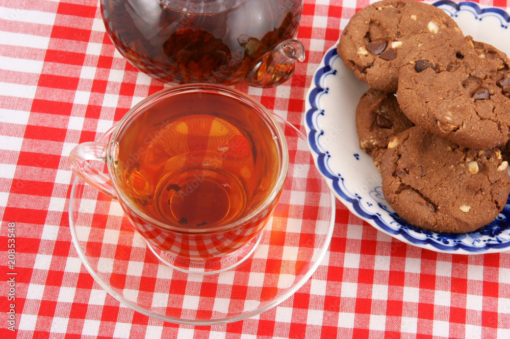 Glass cup of tea, teapot and cookies